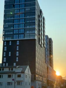 um edifício alto com um pôr-do-sol ao fundo em Rom m/bad i Bodø sentrum em Bodø