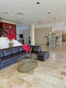 a living room with a black leather couch and a glass table at Altavista Hotel in Reynosa