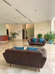 un vestíbulo con 2 sofás de cuero y almohadas azules en Altavista Hotel en Reynosa