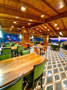 um restaurante com mesas de madeira e cadeiras verdes em AMASRA DADAYLI HOTEL em Amasra