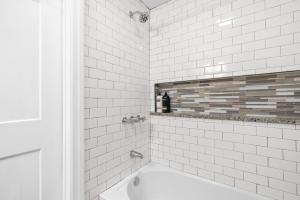 a white tiled bathroom with a bath tub and a window at The Loft At Madison Terrace - Private Unit in Clarksville