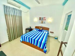 Tamara Motels في هيكادوا: غرفة نوم بسرير وبطانية مخططة باللون الأزرق والأبيض