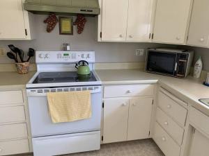 a white kitchen with a stove and a microwave at Fairway Apartments Unit 1 in Twain Harte