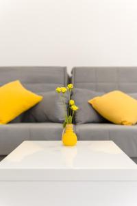 un jarrón amarillo con flores amarillas en una mesa con sofá en Apartments Villa Tudor 1, en Hvar