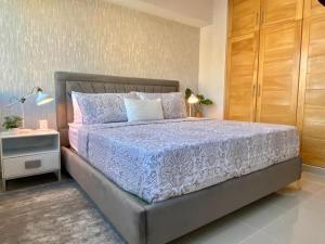 um quarto com uma cama grande e uma mesa de cabeceira em Cozy City Center Condo Full AC em Santo Domingo