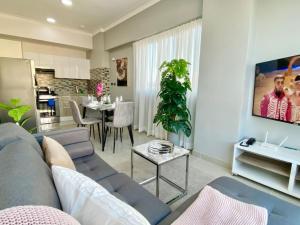 a living room with a blue couch and a kitchen at Cozy City Center Condo Full AC in Santo Domingo