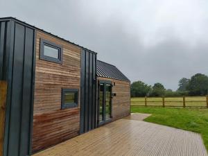 uma casa com uma fachada de madeira e um deque de madeira em The Tiny House em Bovey Tracey