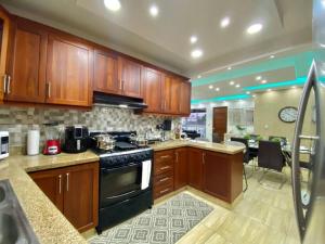 a kitchen with wooden cabinets and a black stove top oven at Gorgeous 3 Bdrm Apartment in Los Prados
