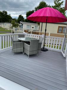 patio ze stołem, krzesłami i różowym parasolem w obiekcie Quince w mieście Ferndown
