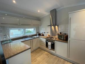 una cucina con armadietti bianchi e frigorifero di Quince a Ferndown
