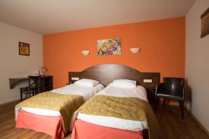 two beds in a hotel room with orange walls at Hotel Van Reeth's Koffiebranderij in Puurs