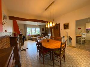 cocina y sala de estar con mesa de madera y sillas en Gîte Au Corti Pierros, en Houyet