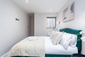 a bedroom with a bed with a green headboard and white pillows at The Stylish Spot 1 Bed Apt in Leeds City Centre in Leeds