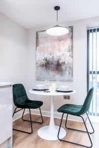 a dining room with a white table and two green chairs at The Stylish Spot 1 Bed Apt in Leeds City Centre in Leeds
