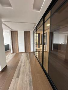 an empty living room with glass walls and wood floors at Mar Apartamentos in Bucaramanga