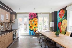 una cocina con una mesa larga con sillas y flores pintadas en las paredes. en The Hipstel Parallel en Barcelona