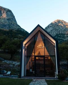 a small house with large windows and mountains in the background at North Alpine Villas in Bogë