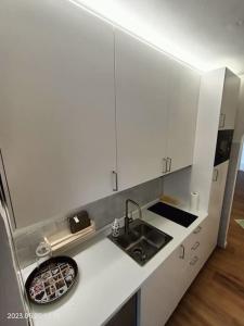 - une cuisine blanche avec évier et comptoir dans l'établissement Alloggio Asiago Centro (appartamento nuovo), à Asiago