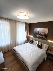 a bedroom with a large white bed with a painting on the wall at Alloggio Asiago Centro (appartamento nuovo) in Asiago