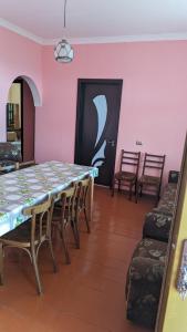 uma sala de jantar com uma mesa e cadeiras e paredes cor-de-rosa em Guest house 