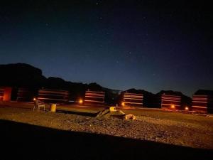 una escena nocturna de un patio de trenes con luces en Wadi rum secrets camp, en Wadi Rum