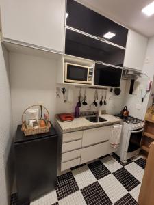 a small kitchen with a sink and a microwave at Apê Turquesa, 190 m da praia do Leme in Rio de Janeiro