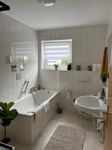 a white bathroom with a tub and a sink at Ferienwohnung Milla in Weissach Im Tal