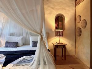 a bedroom with a bed with curtains and a table at Soleluna Casa Pousada in Trancoso