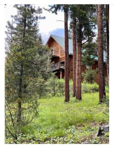 una casa de madera en el bosque con árboles en Cerul Mare Cabin en Gallatin Gateway