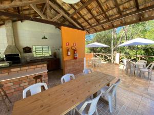 un patio con mesa de madera, sillas y sombrillas en Pousada Sotaque Mineiro, en Cunha