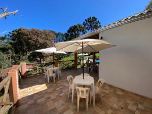 a patio with tables and chairs and umbrellas at Pousada Sotaque Mineiro in Cunha