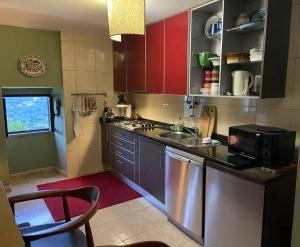 a kitchen with red cabinets and a stainless steel dishwasher at Casa Pero Soares in Guarda