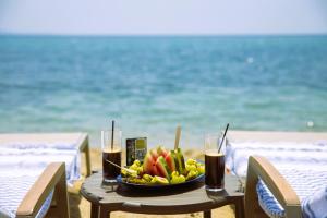 Elaiokhórion的住宿－Anasa Luxury Resort，海滩上的一张桌子,上面放着一碗水果和饮料