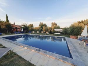 a large swimming pool in a yard with a table at Cortona Holiday Home in Cortona