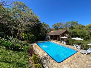 a swimming pool with two chairs and a house at Pousada Sotaque Mineiro in Cunha