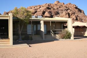 a house in front of a pile of rocks at Namib Naukluft Lodge in Solitaire