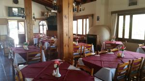 a dining room with red tables and chairs and windows at Pelekanos Apartments in Pissouri