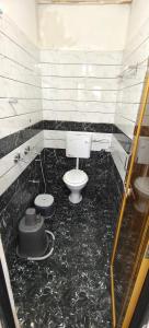 a bathroom with a toilet and a black floor at HOTEL ANJALI in Ujjain