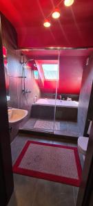 La salle de bains est pourvue d'un éclairage rouge, d'une baignoire et d'un lavabo. dans l'établissement MAZURSKI DOM, à Orzysz