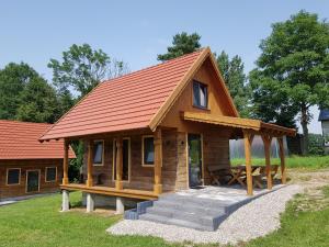 małą drewnianą kabinę z pomarańczowym dachem w obiekcie Kraina Biebrzy - domki nad Biebrzą w mieście Wroceń