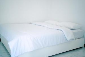 Cama blanca con sábanas y almohadas blancas en Getrudis Guesthouse, en Labuan Bajo