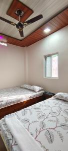 2 camas en una habitación con ventilador de techo en HOTEL ANJALI en Ujjain