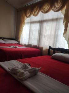 a bedroom with two beds with red sheets and a window at Hotel Casa Real 2 in Popayan