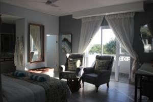 1 dormitorio con 1 cama y 2 sillas y balcón en Ecolux, en Marracuene