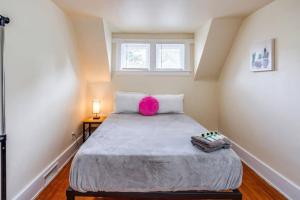 a bedroom with a large bed with a pink pillow at Marvelous Colonial Mins to UofR/Airpt in Rochester