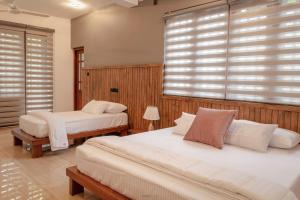 1 dormitorio con 2 camas y una ventana con persianas en River Breeze Residents, en Kandy