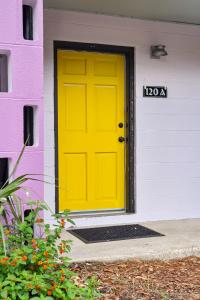 a yellow door on a purple and white house at Folly Vacation Great Location, Vintage and Fun 120 Unit A in Folly Beach