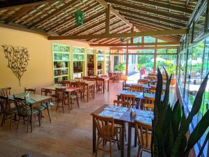 an empty restaurant with tables and chairs and windows at Hotel Solar Fazenda Do Cedro in Itaipava