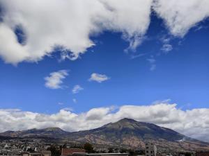 vistas a la ciudad y a una montaña con nubes en Hotel Altamira Suites - Ibarra en Ibarra