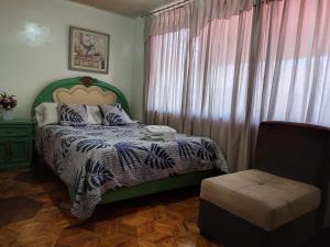 a bedroom with a green bed and a chair at Hotel Altamira Suites - Ibarra in Ibarra
